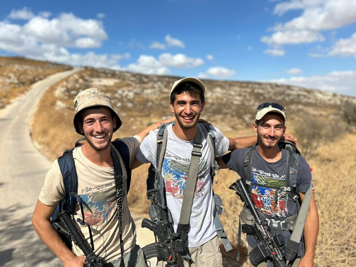 שלושה מדריכים עם תרמילים על דרך עפר